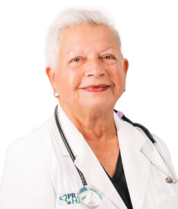 Doctor Elvira Rives in a white coat staring at the camera with a stethoscope on her.