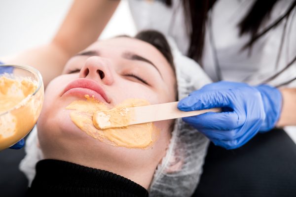 Beautician applying facial mask at cosmetic clinic, cosmetology treatment skincare face
